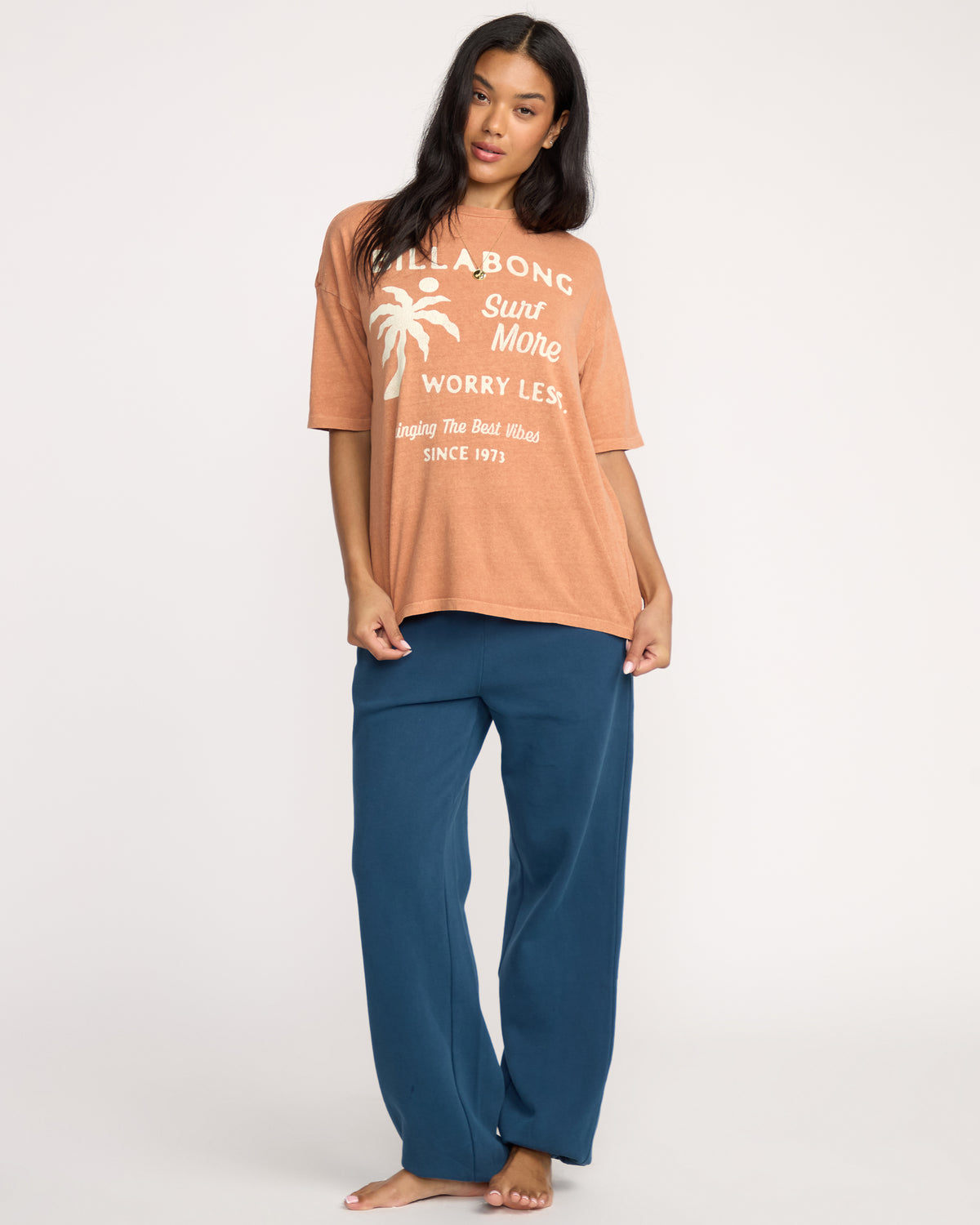 Sunburnt short-sleeve tee with white text and palm tree graphic on front, paired with blue pants.