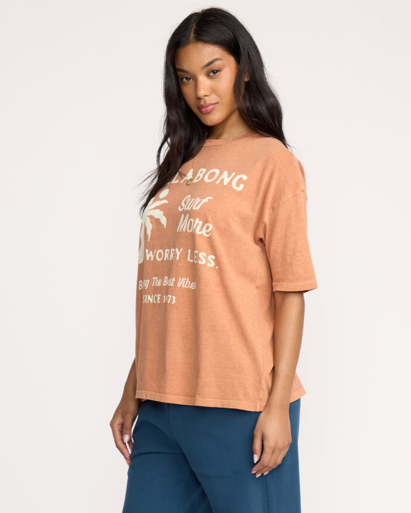 Sunburnt-colored short sleeve tee with white graphic text and palm leaf design on back.