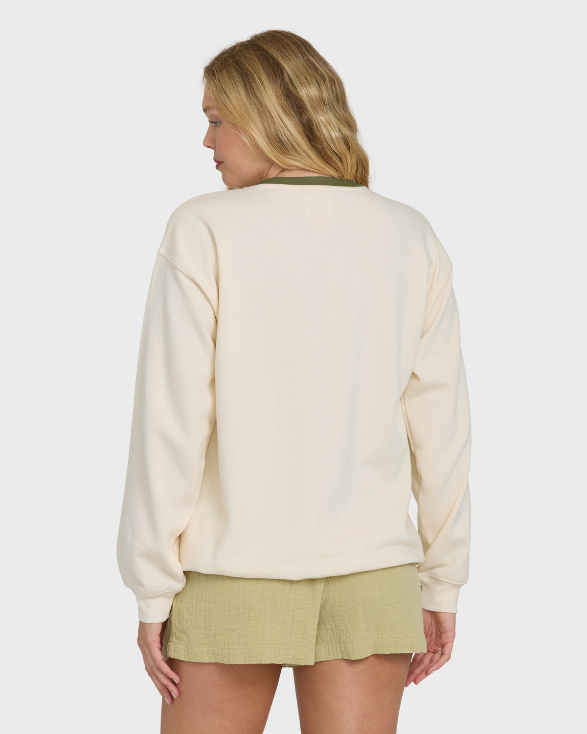 White crewneck sweatshirt with long sleeves worn with a light green skirt, shown from back view.