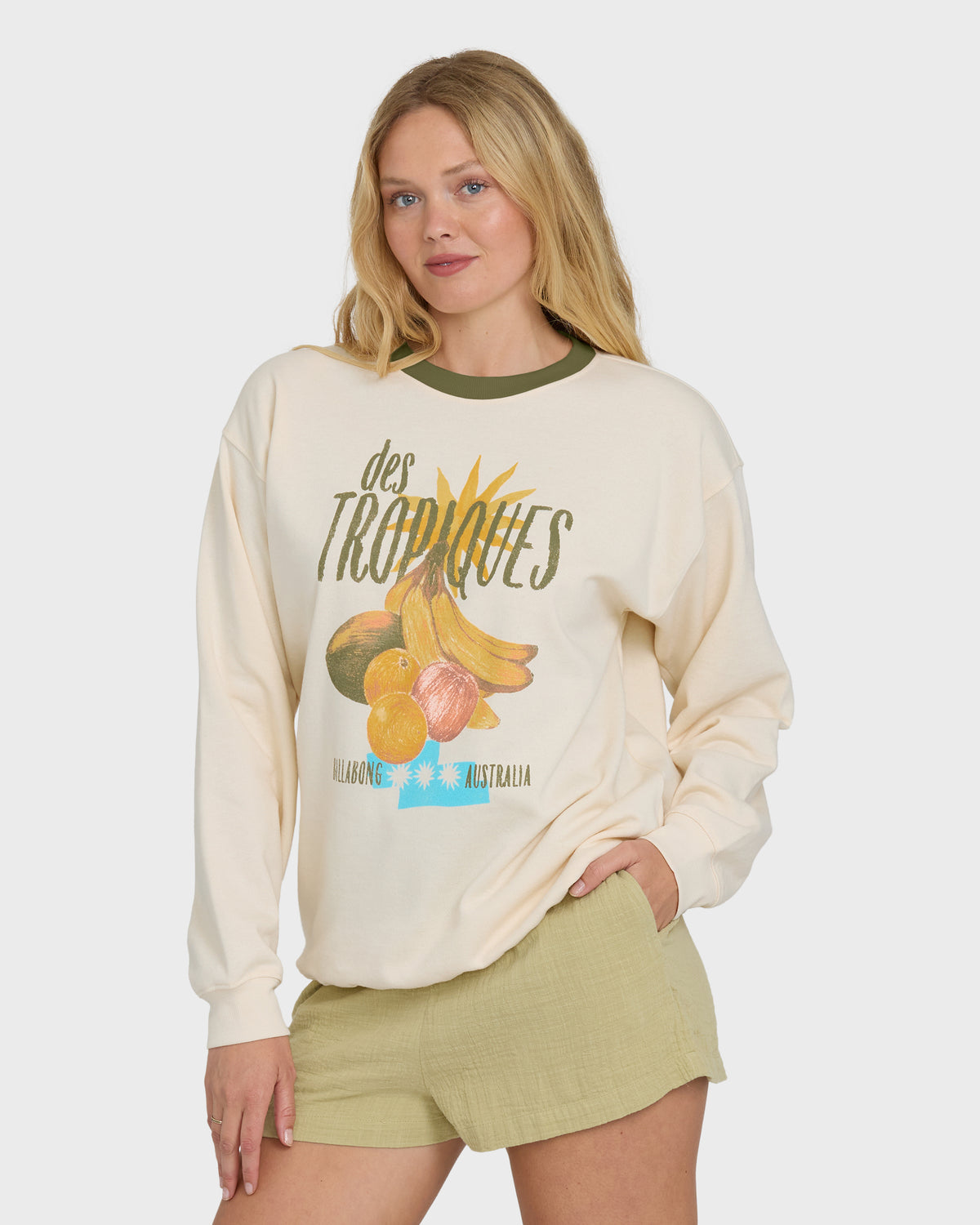 White crewneck sweatshirt with "des Tropiques" fruit graphic and green ribbed collar trim.