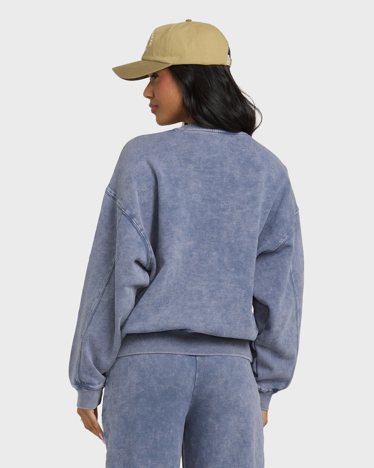 Stone blue crewneck sweatshirt with saltwashed finish, shown from back on model wearing tan baseball cap.