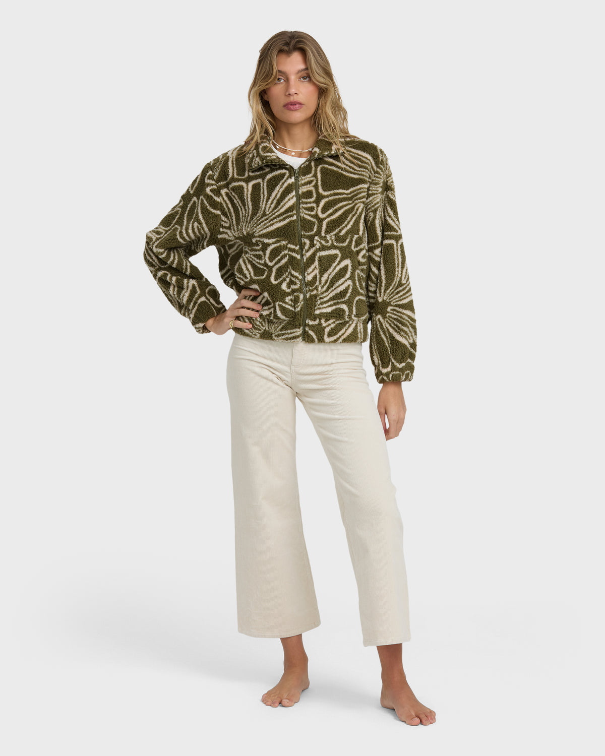 Olive and cream sherpa fleece jacket with abstract line pattern and front zip closure, worn with cream pants.