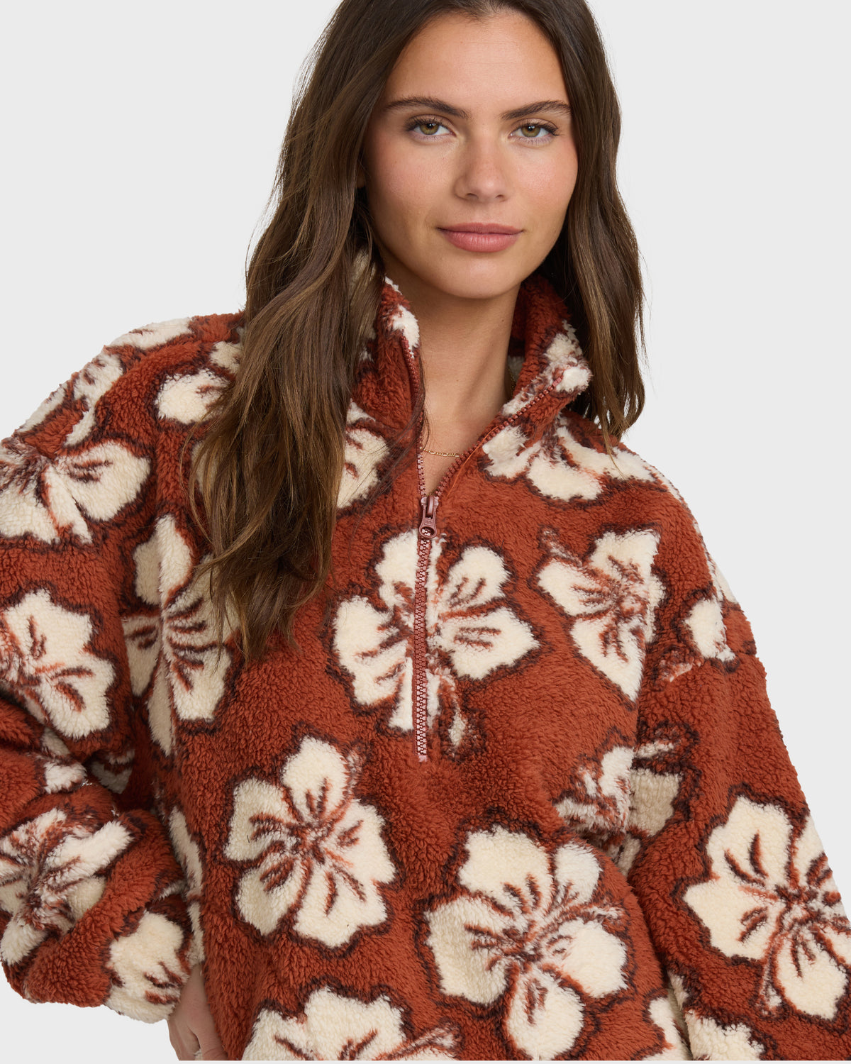 Rust-colored sherpa half zip sweatshirt with cream floral pattern and textured fleece fabric.