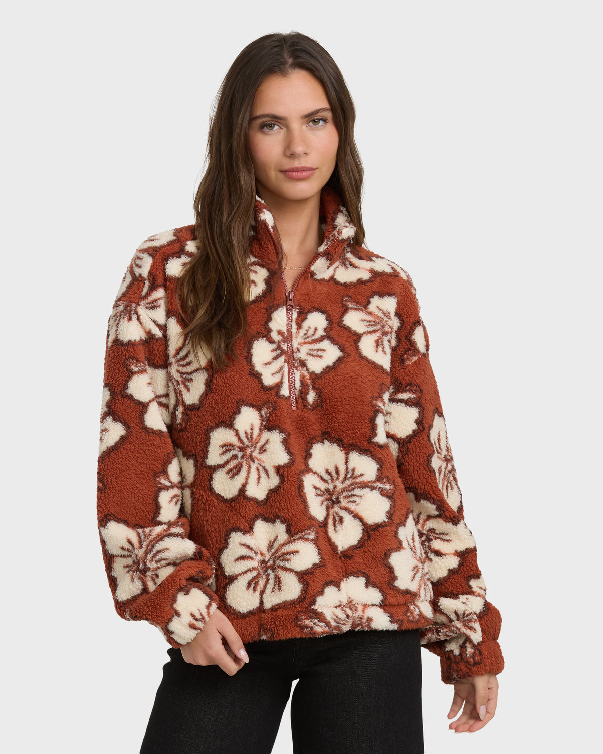 Rust-red sherpa half-zip sweatshirt with cream floral pattern, worn with black pants.