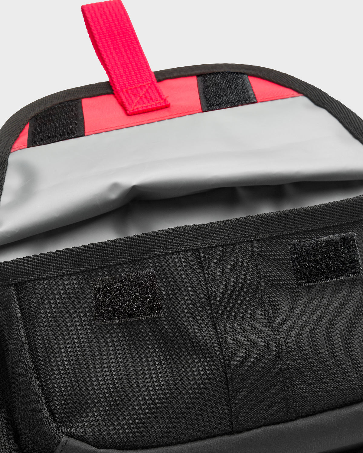 Black waistpack with pink and black striped interior, pink carry handle, and white padded lining visible.
