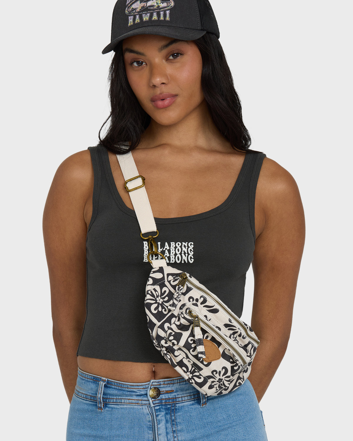 Black and white patterned waistbag with cream shoulder strap and gold hardware, worn across torso.
