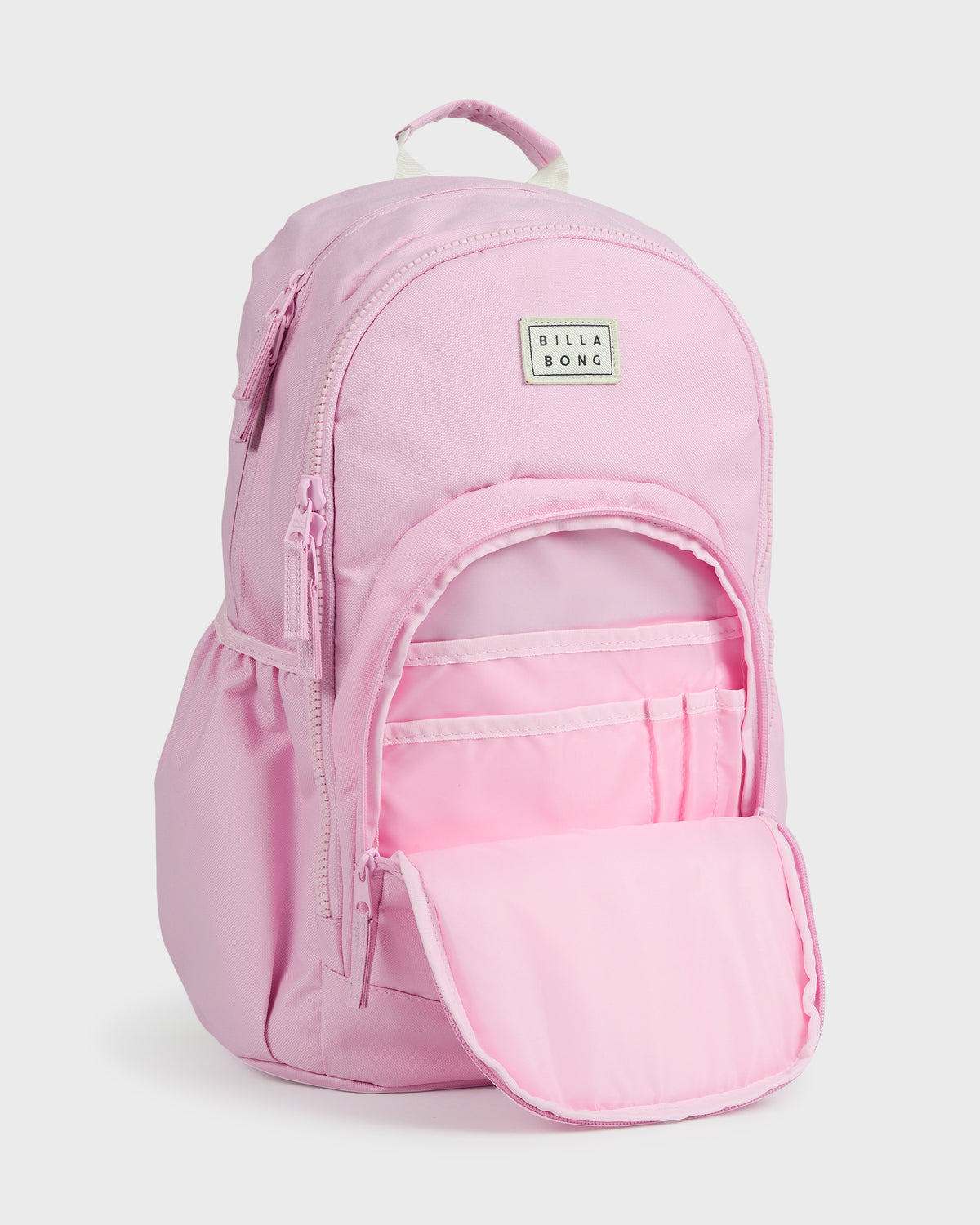Light pink backpack with top handle, front zippered pocket open showing interior compartments, and Billabong logo patch.