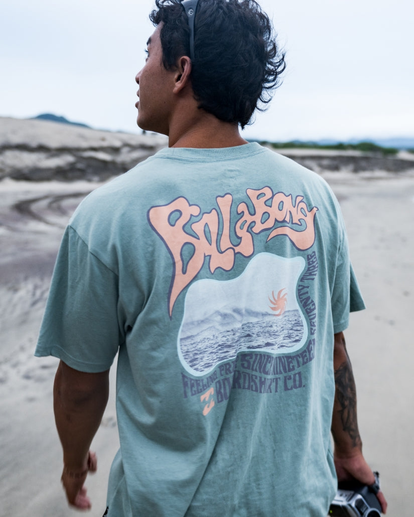 Mineral blue short sleeve t-shirt with coral and purple graphic print on back featuring wave design and text.