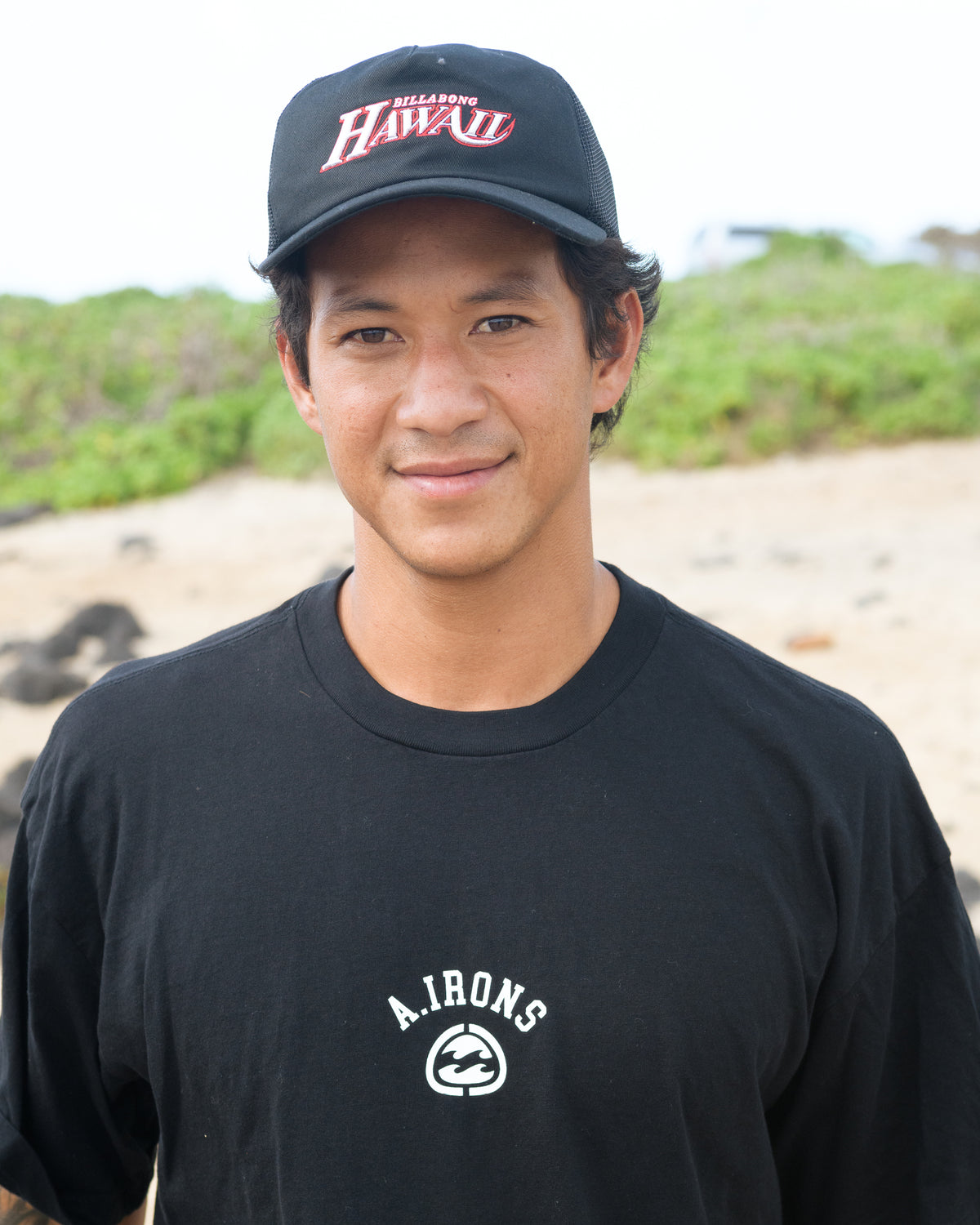 Black trucker hat with mesh panels and red "Billabong" logo on front.