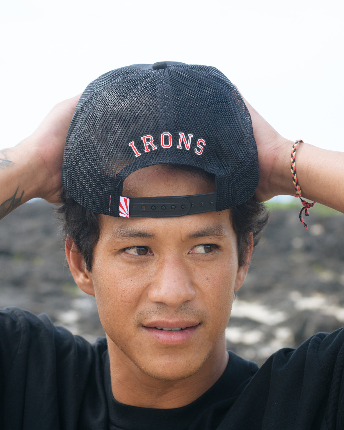 Black trucker hat with mesh back panel, "IRONS" embroidered on front, and adjustable snap closure strap.