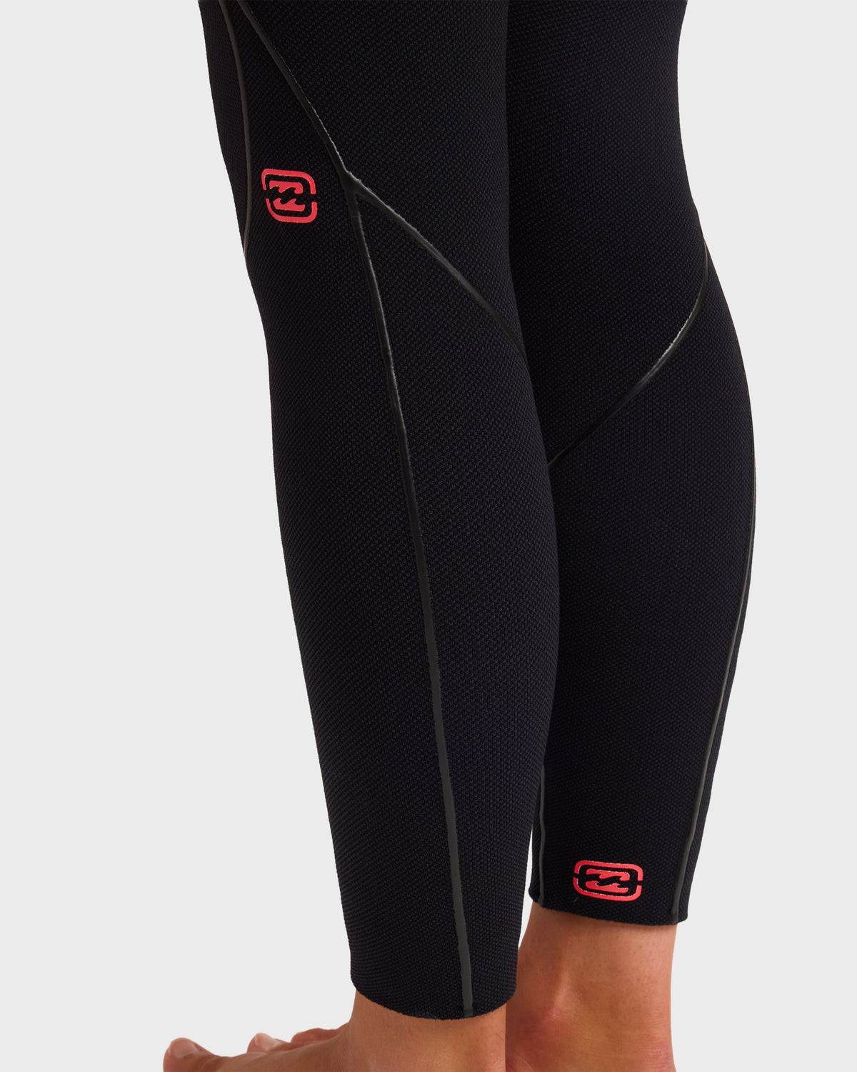 Black full-length wetsuit with textured neoprene fabric, red brand logo on thigh and ankle, flat-lock seam stitching visible 