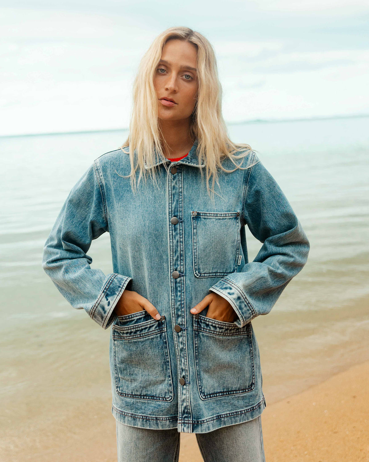 Medium-wash denim chore coat with chest and front patch pockets, button front, and rolled cuffs.