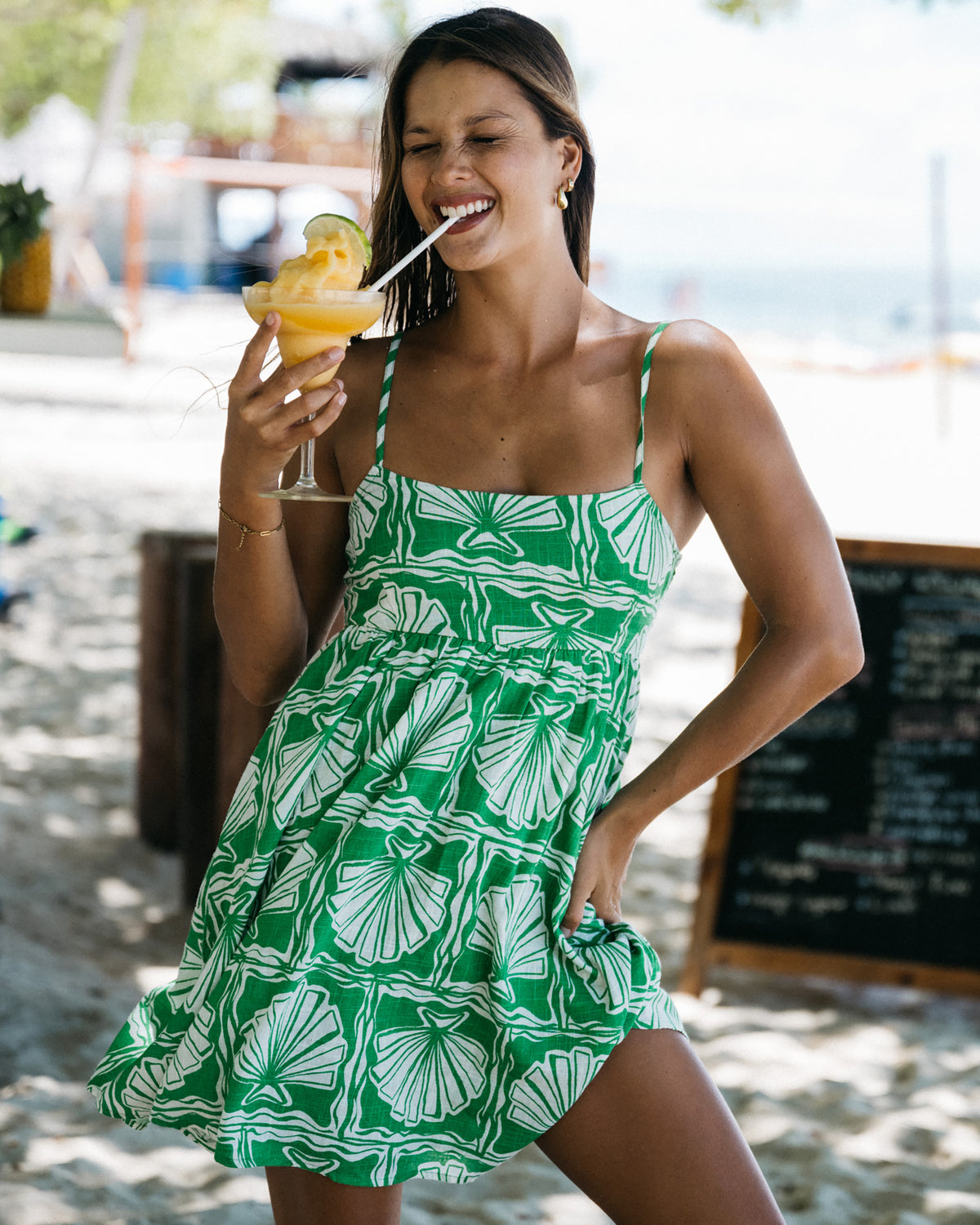 Kelly green mini dress with white shell print, thin straps, and smocked bodice detail.