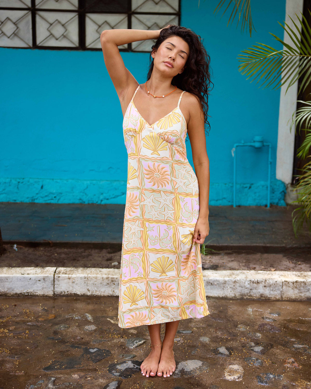 Sleeveless midi dress with lilac, yellow, and orange shell and sun print on cream background.