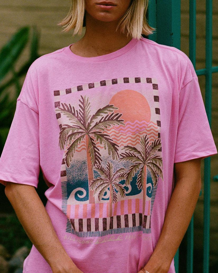 Pink short-sleeve knit t-shirt with tropical graphic print featuring palm trees, sun, and geometric patterns.