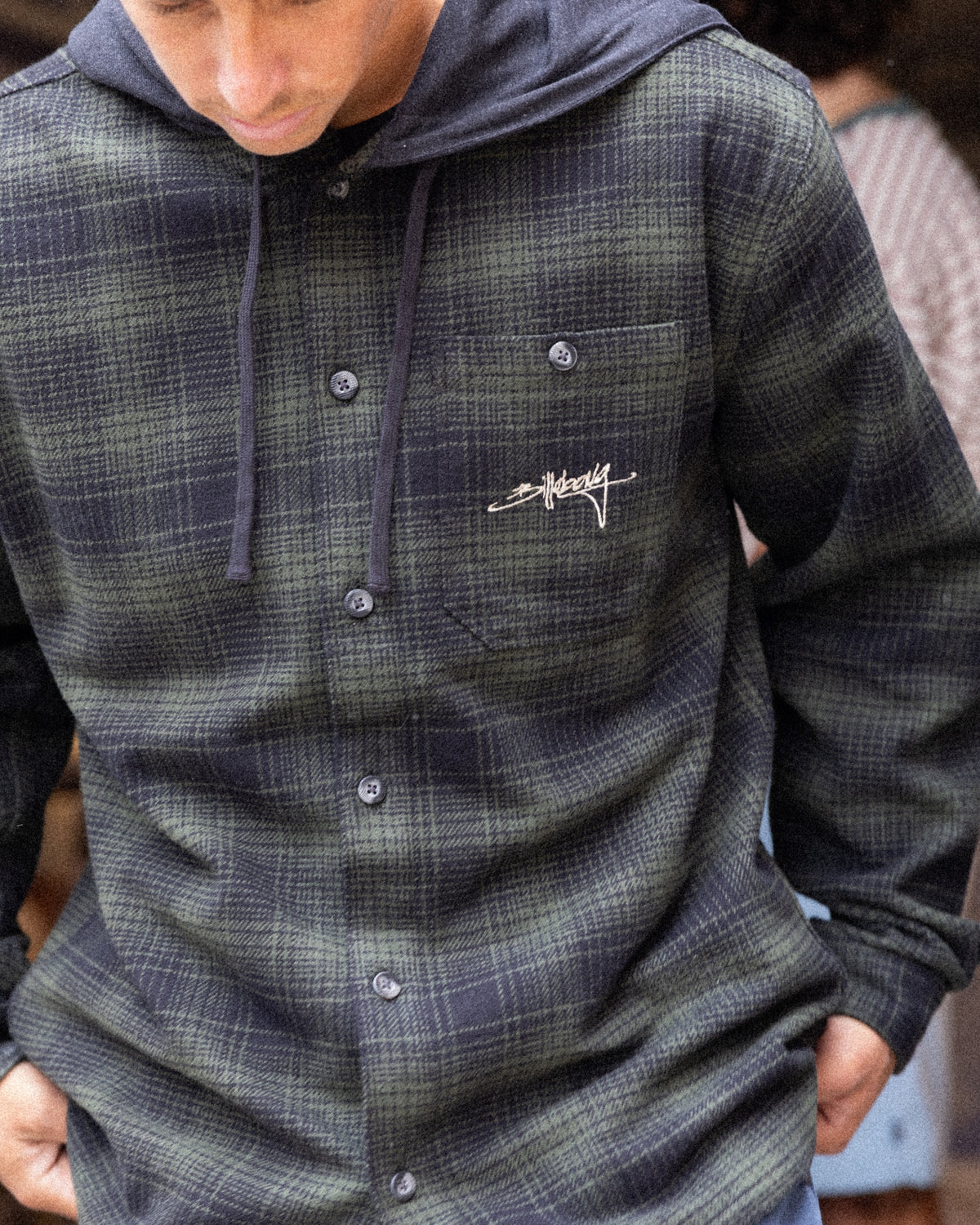 Black and gray plaid flannel shirt with hood and button front closure.