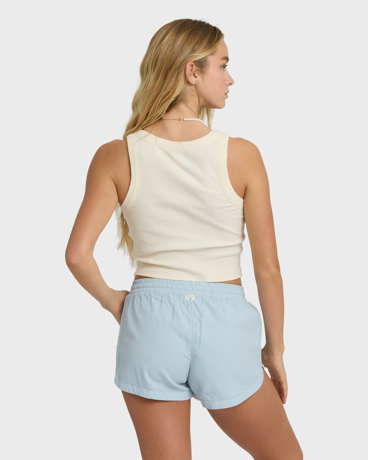 Washed chambray shorts with elastic waist and curved hem, worn with cream ribbed tank top.
