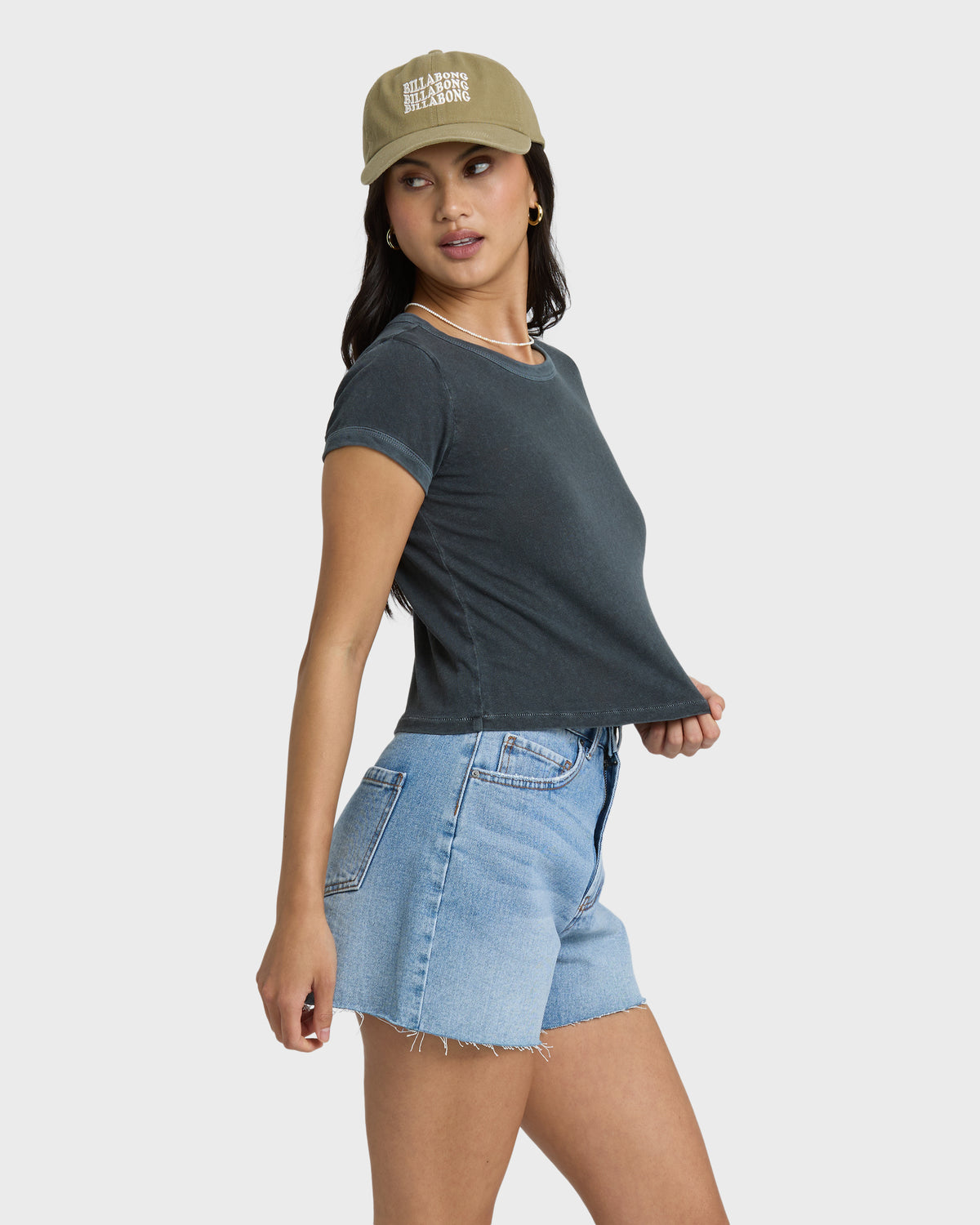 Faded indigo denim cut-off shorts with frayed hem and pocket detail, styled with dark t-shirt.