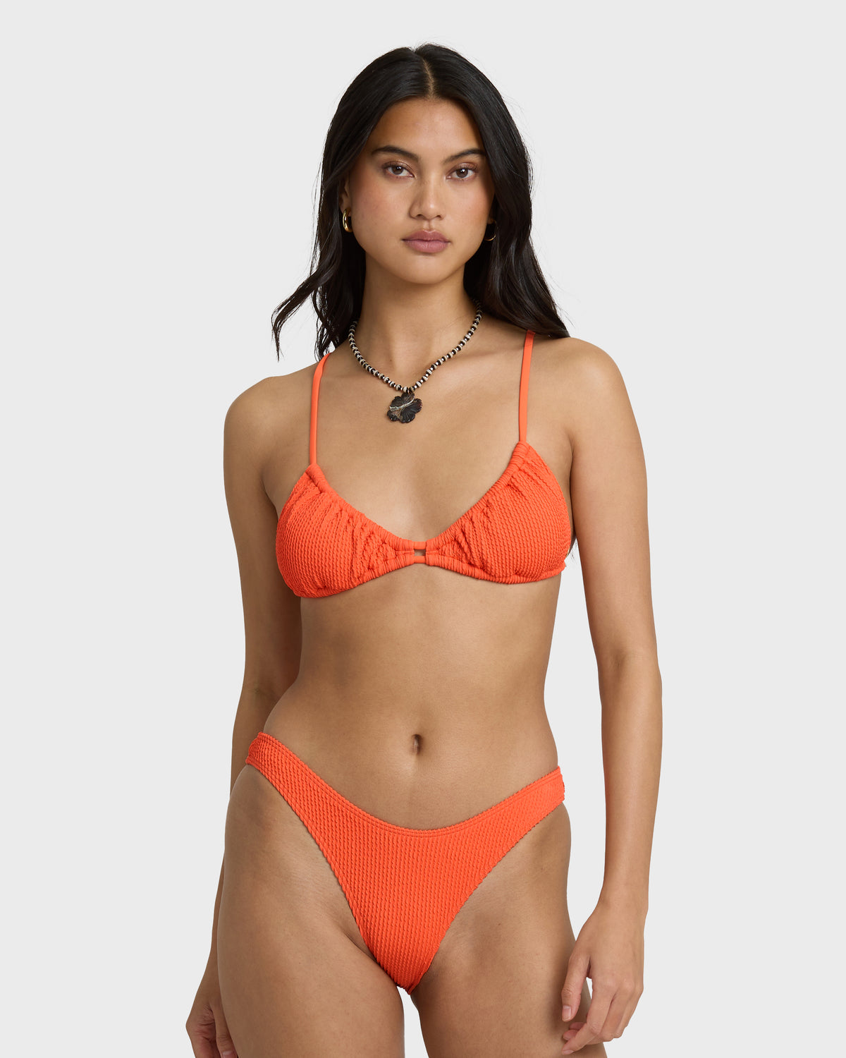 Hot coral textured bikini bottom with high-rise cut on model.