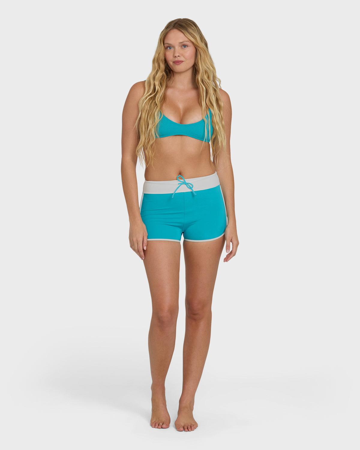 Bright turquoise boardshorts with white waistband and drawstring tie, worn with matching bikini top.