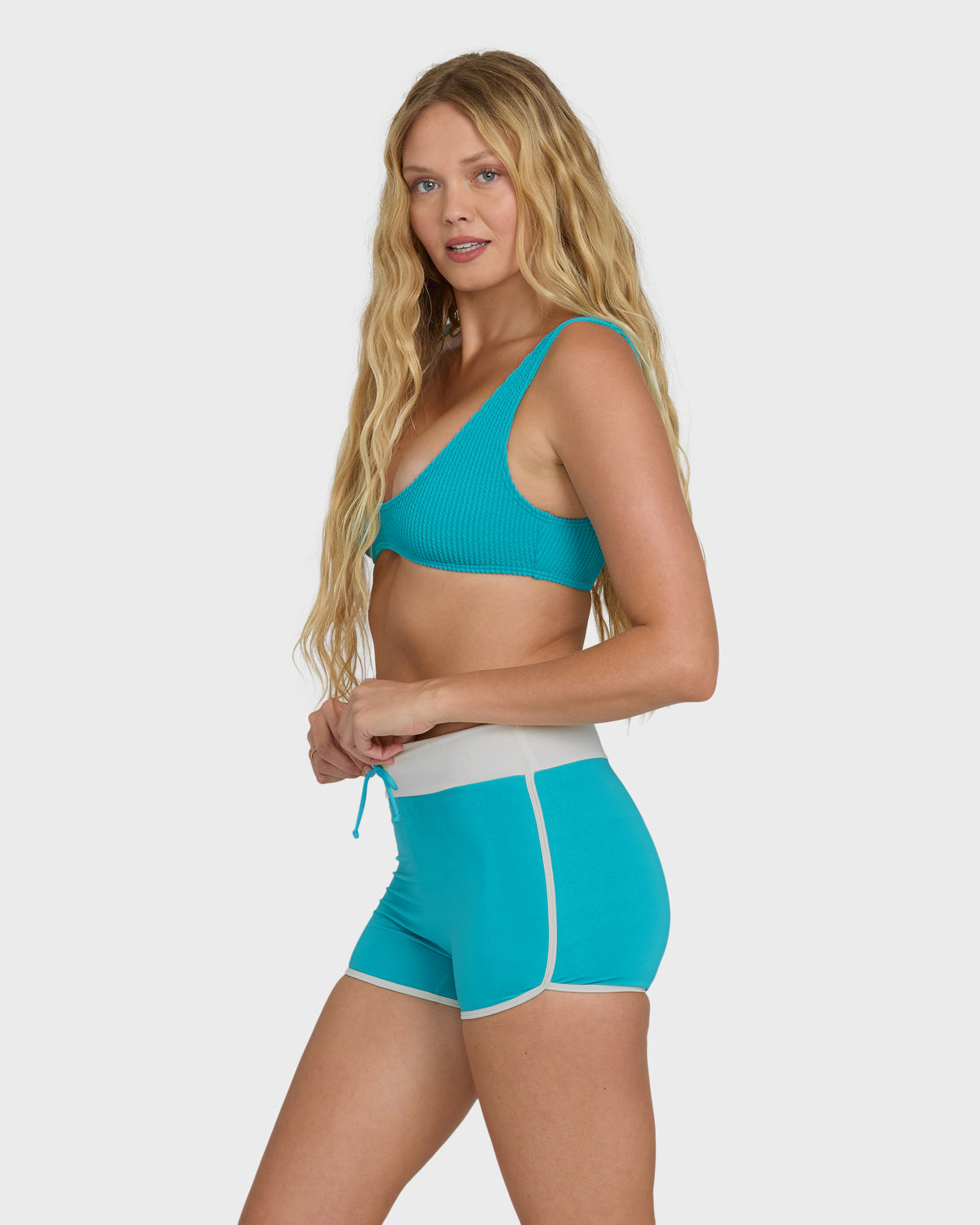 Bright turquoise boardshorts with white trim and drawstring tie, worn with matching bikini top.