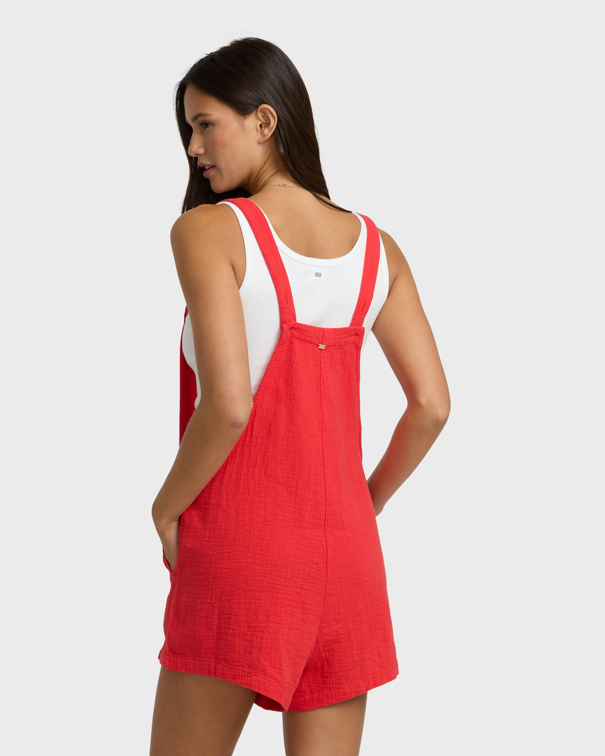 Red and white sleeveless romper with adjustable straps and front pockets.