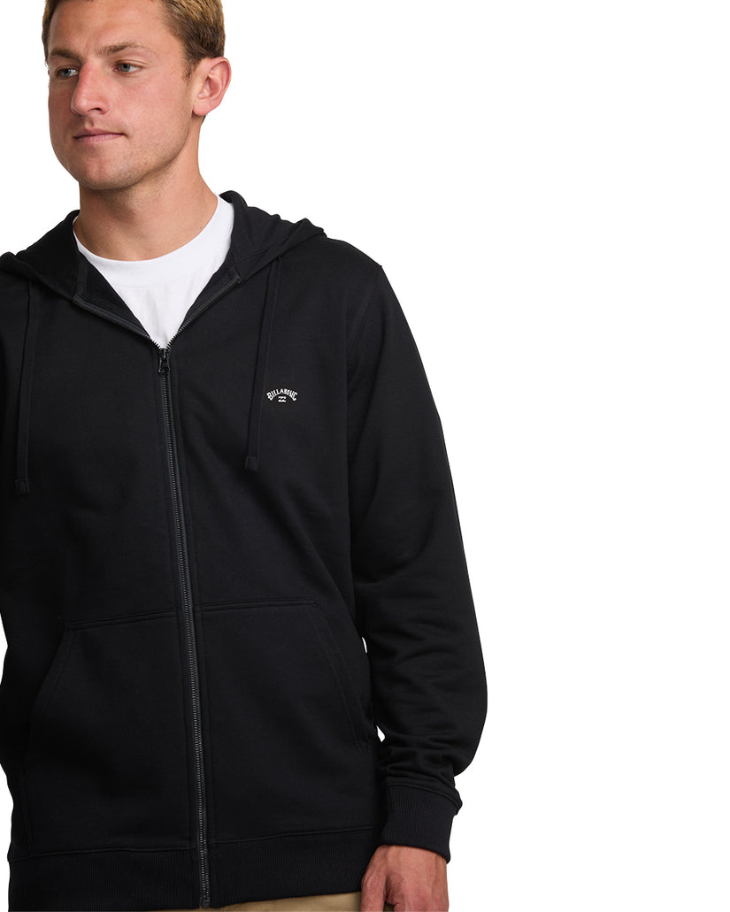 Man wearing black zip-front hoodie with white t-shirt underneath and drawstring hood.