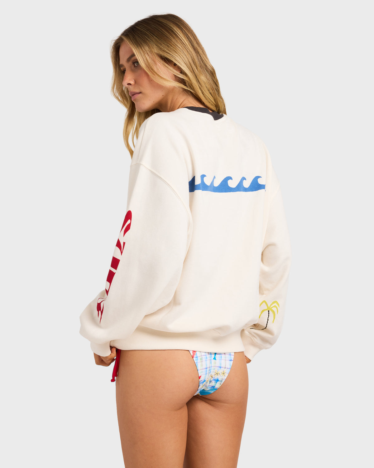 Cream crewneck sweatshirt with blue wave graphic on back, red text on sleeve, and yellow detail on cuff.