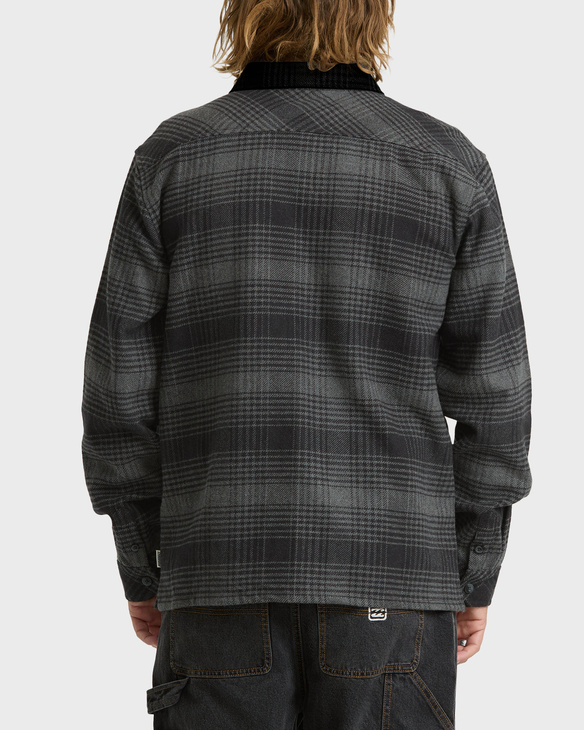 
Back view of a person wearing a gray and black plaid long sleeve shirt with a dark collar and black work pants.