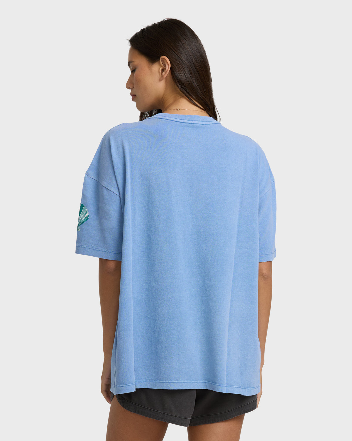 Blue short-sleeve cotton t-shirt with small graphic on sleeve, shown from back view on model.