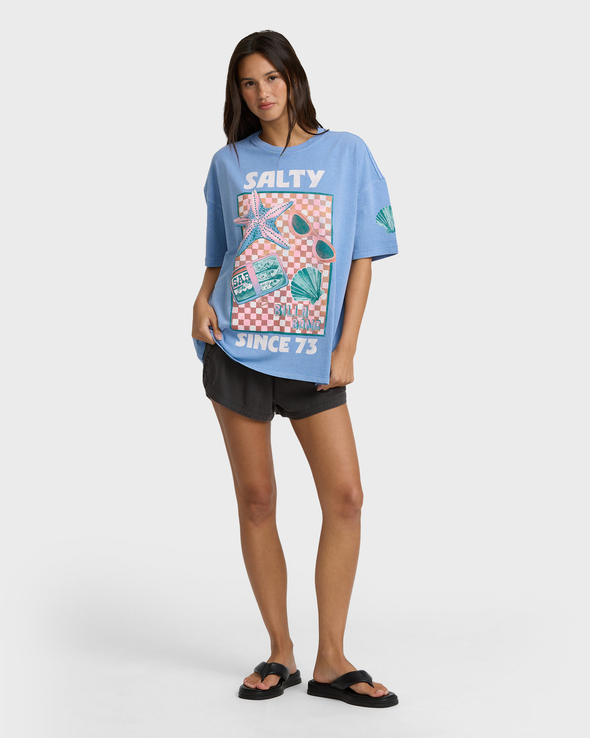 Blue short-sleeve t-shirt with "Salty" graphic print featuring checkered pattern, starfish, sunglasses, and shells.