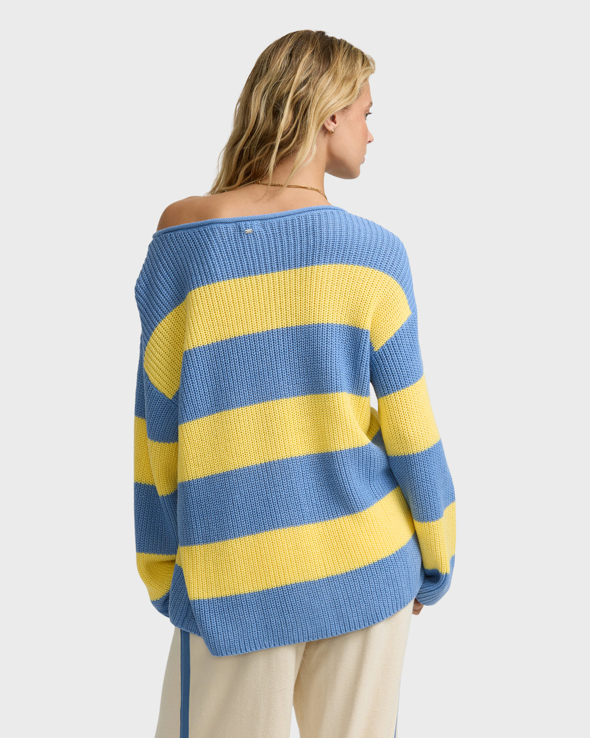 Blue and yellow striped off-shoulder ribbed sweater with long sleeves worn by model from back view.