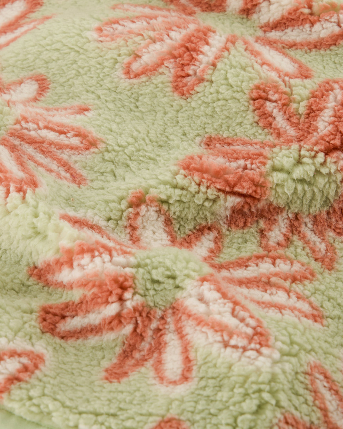 Close-up of a textured fabric with floral patterns in red and white on a green background