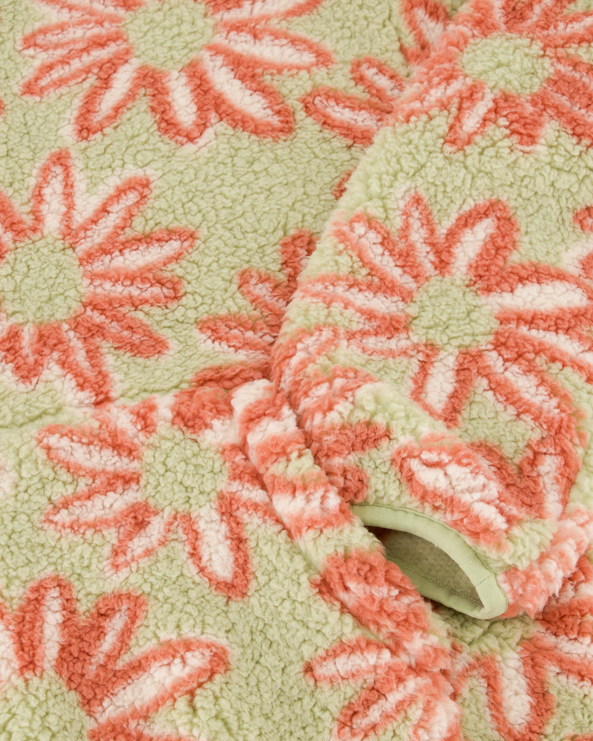 Close-up of a textured fabric with pink floral patterns on a green background