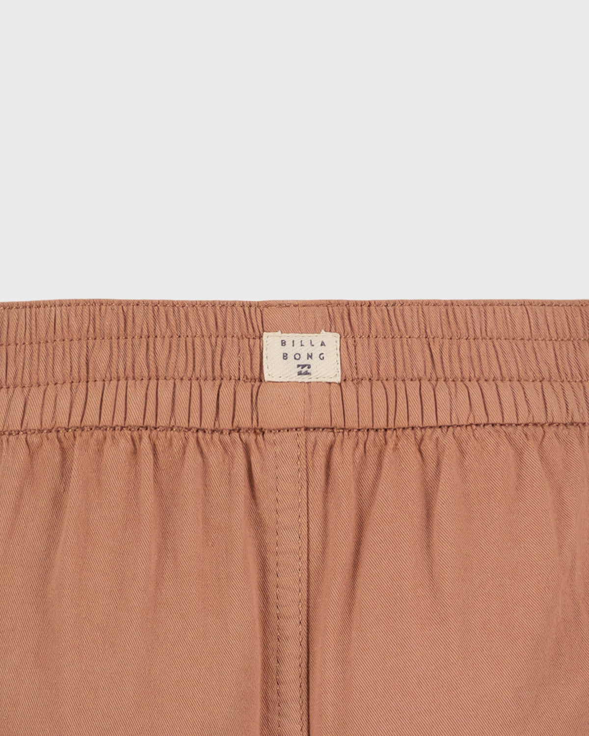 Close-up of a brown garment with a visible brand label on a light gray background