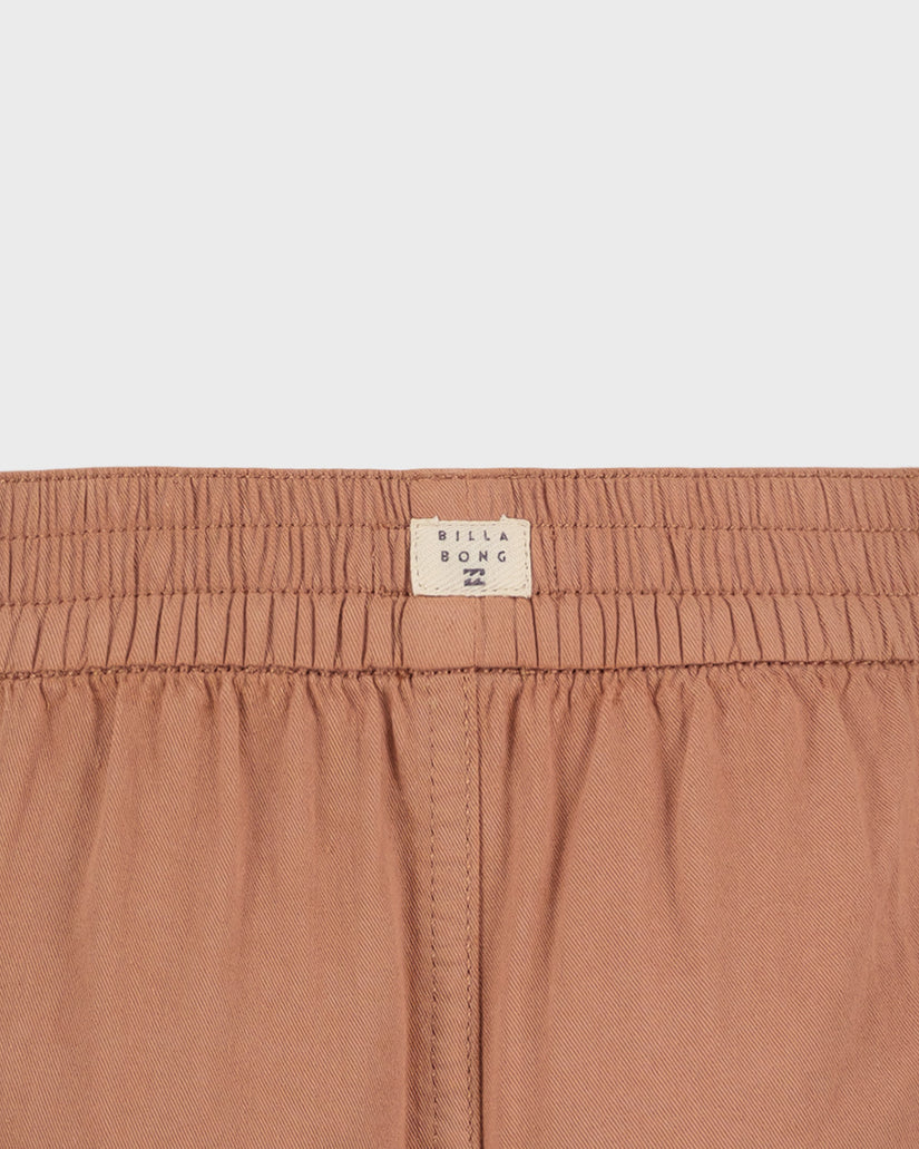 Close-up of a brown garment with a visible brand label on a light gray background