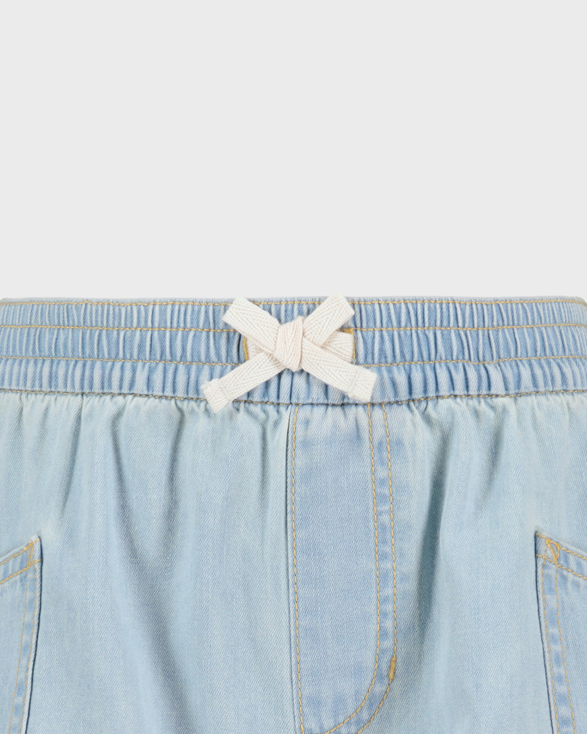 Light blue denim shorts with a white bow on a light gray background