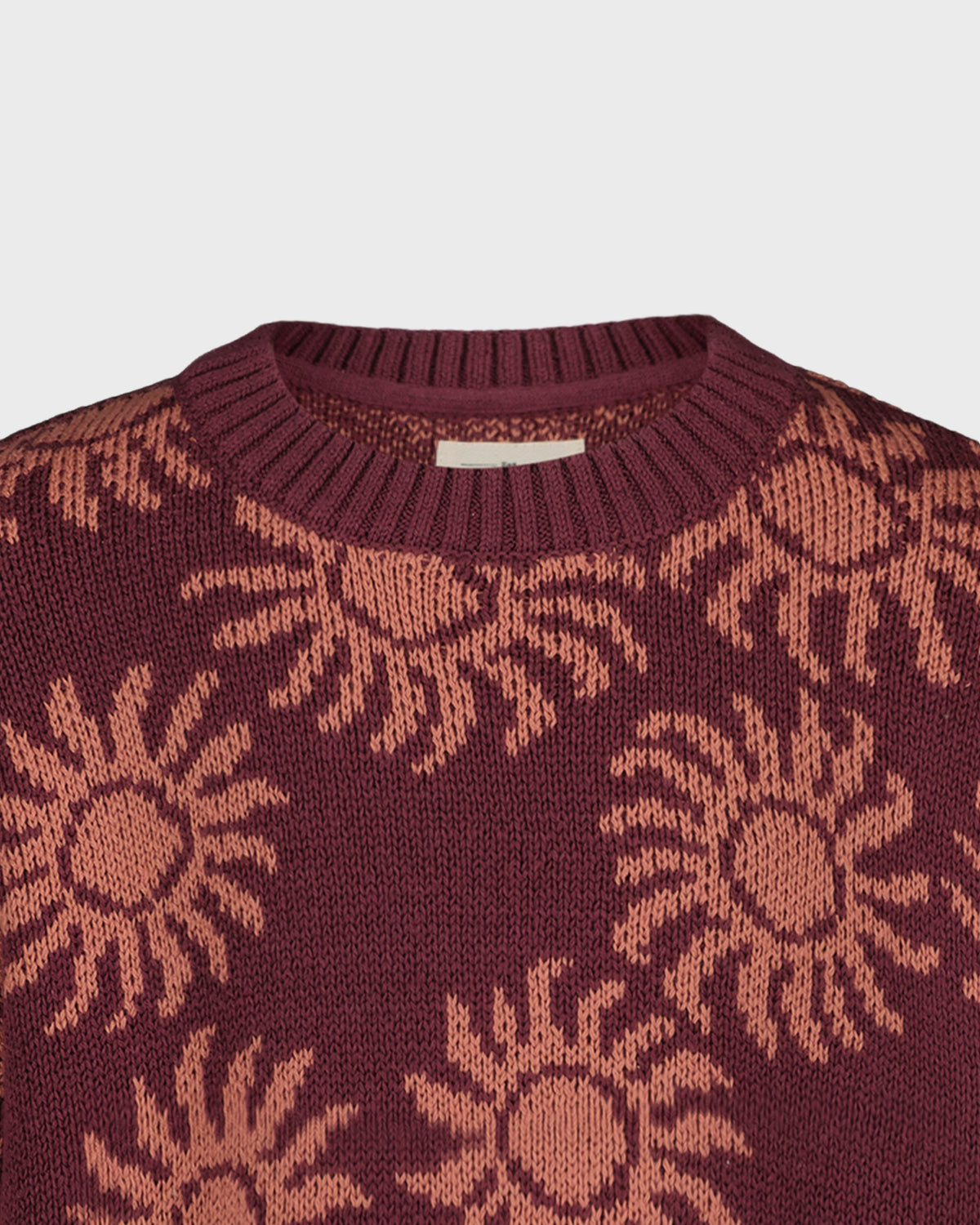 Maroon sweater with sun pattern on a light gray background