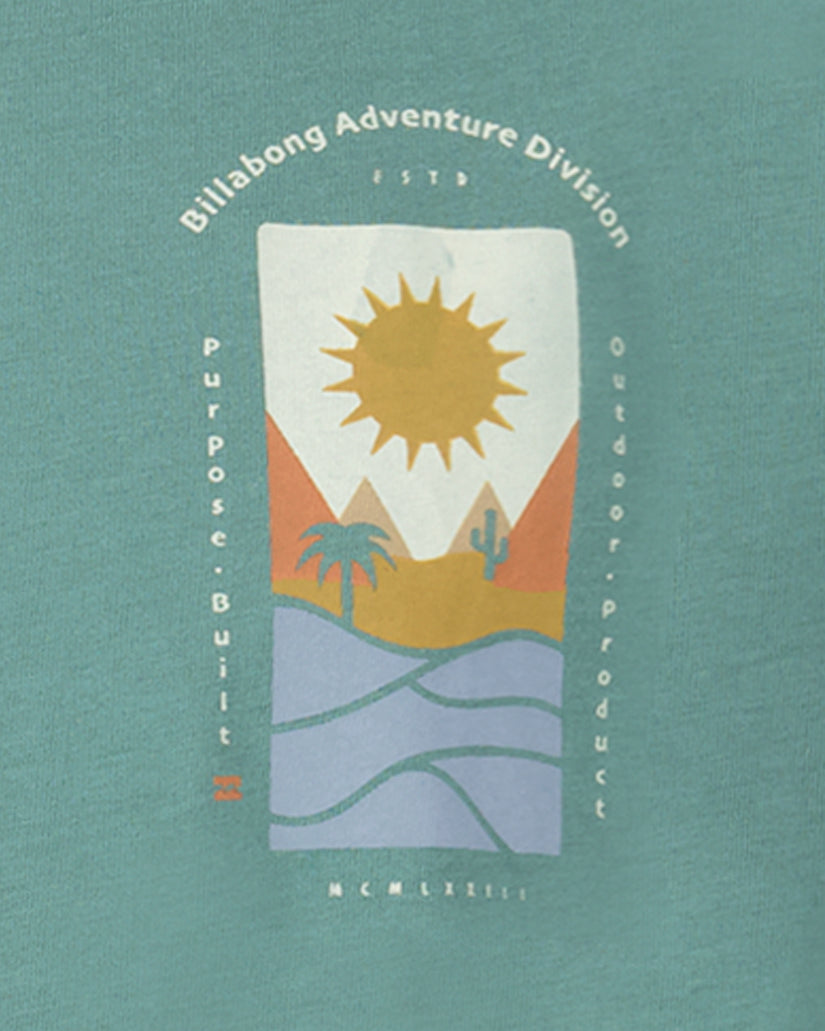 Teal t-shirt with centered graphic featuring sun, desert landscape, palm trees, and "Billabong Adventure Division" text.