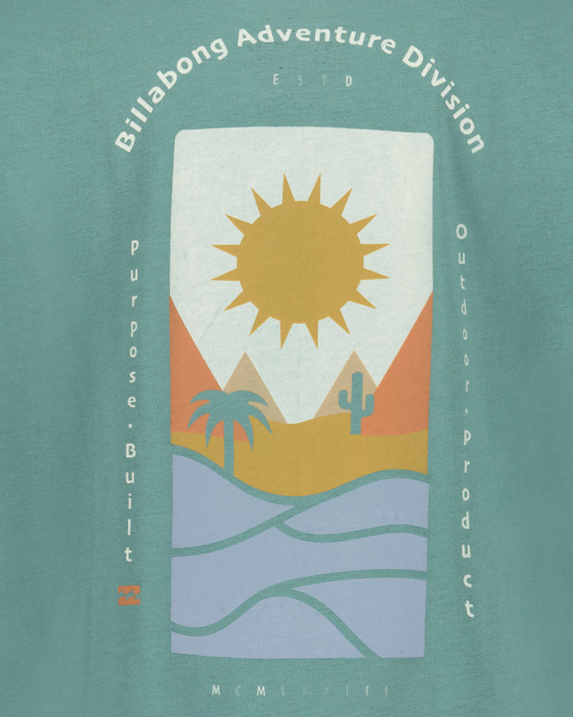 Teal short sleeve t-shirt with geometric desert landscape graphic featuring sun, cactus, palm tree, and water waves with text
