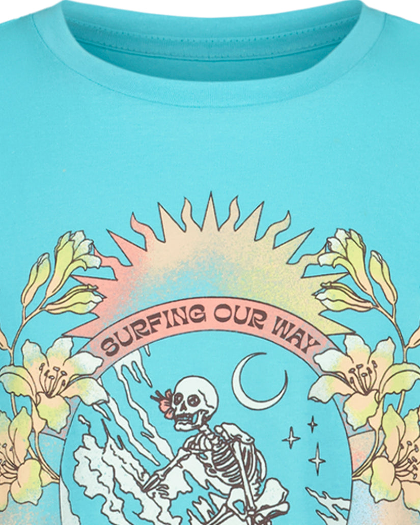 Turquoise t-shirt with graphic print featuring skeleton surfer, sun, flowers, and "Surfing Our Way" text.