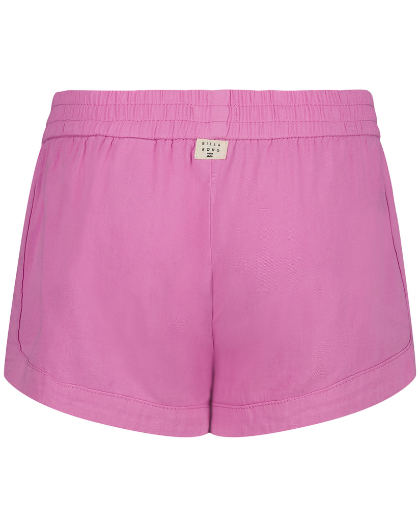 Pink shorts with elasticated waistband and curved seams, back view with Billabong label visible.