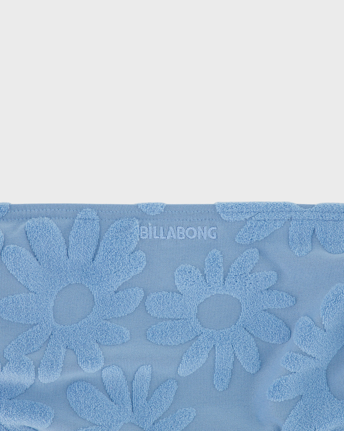 Blue towel with floral patterns and 'Billabong' branding on a light gray background