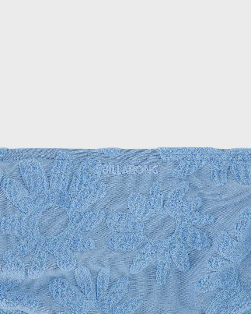 Blue towel with floral patterns and 'Billabong' branding on a light gray background