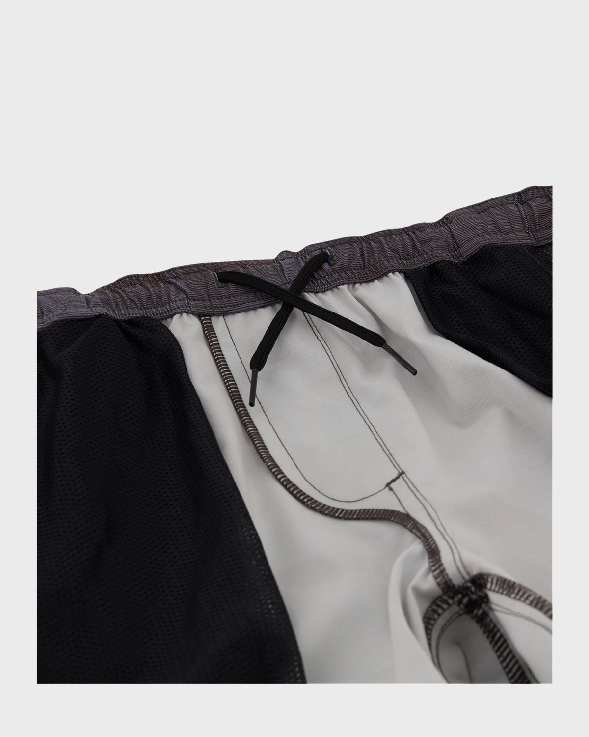 Boys shorts with black outer layer, white inner lining, elastic waistband with drawstring tie, and visible seam stitching.