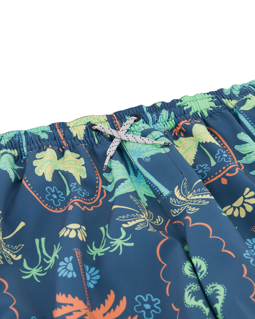Navy swim trunks with colorful floral and botanical print in green, yellow, and orange, featuring an elastic waistband with w