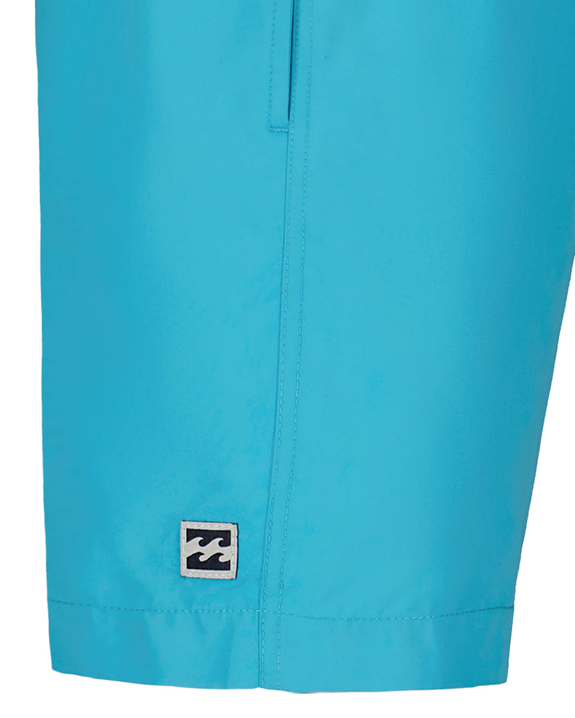 Turquoise swim trunks with center seam and small wave logo patch near hem.