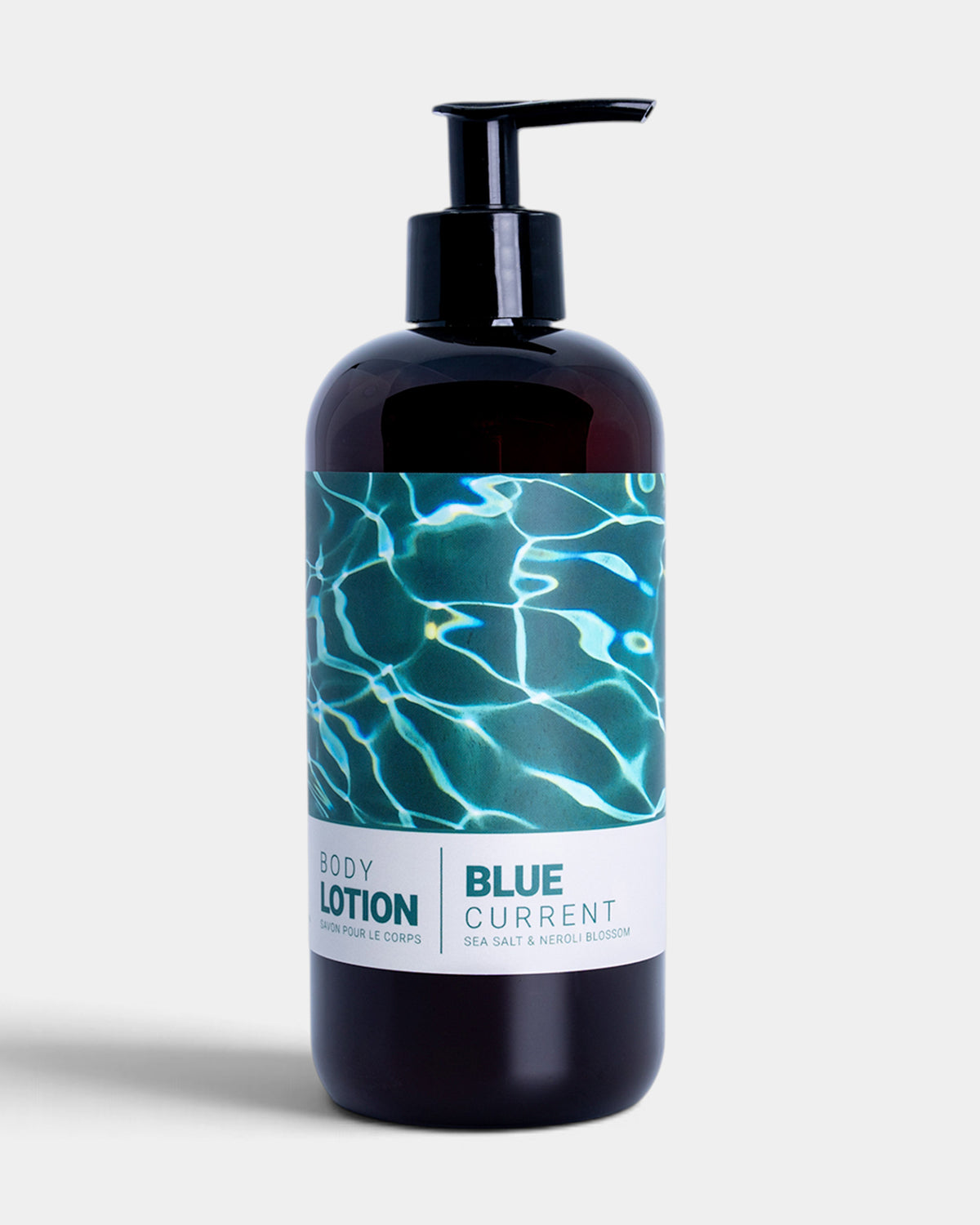 A dark amber bottle of body lotion with a black pump dispenser and a label featuring a blue water ripple design, set against a light gray background.