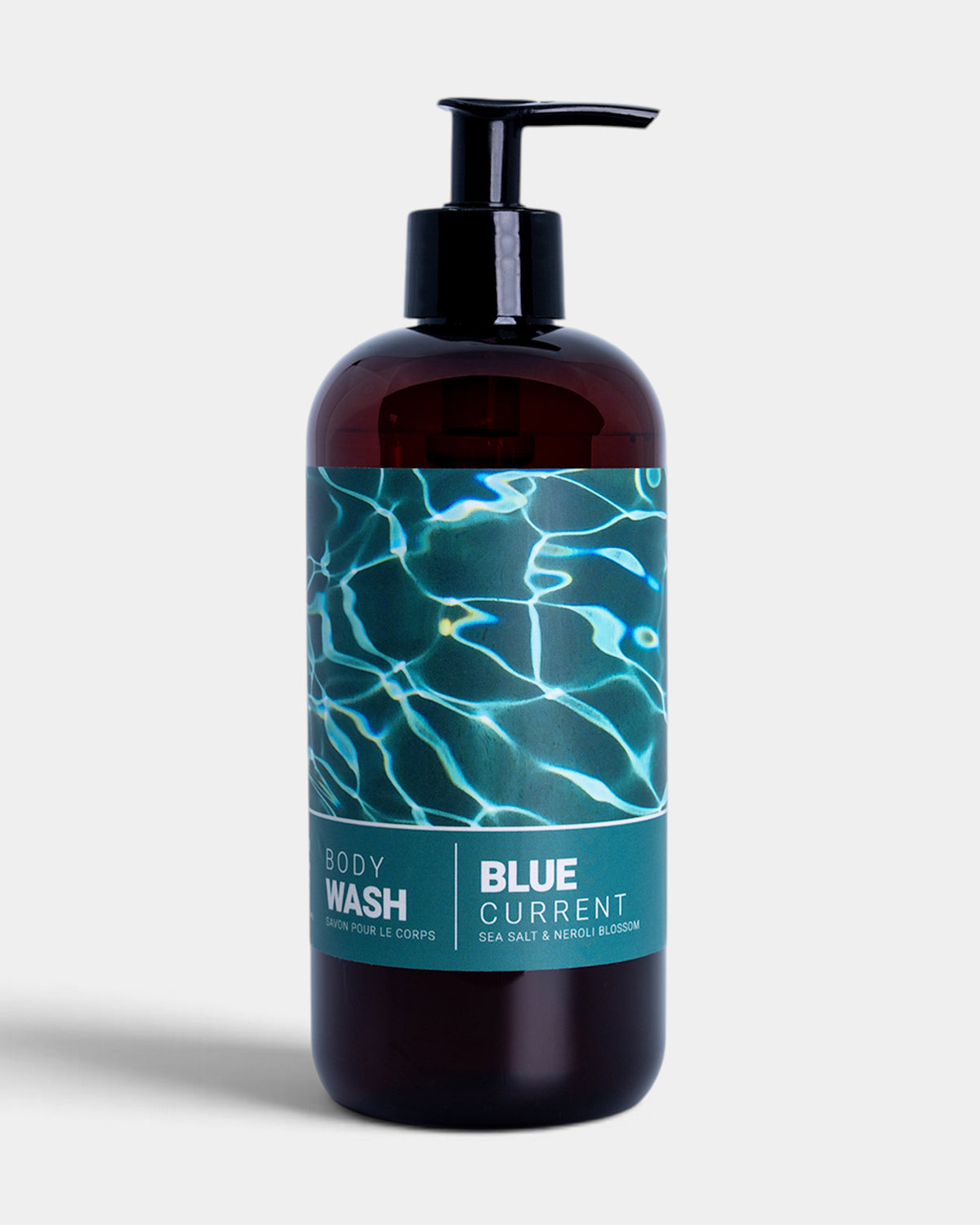 Dark glass pump bottle labeled "Blue Current Body Wash" with teal water-pattern label and black pump dispenser.