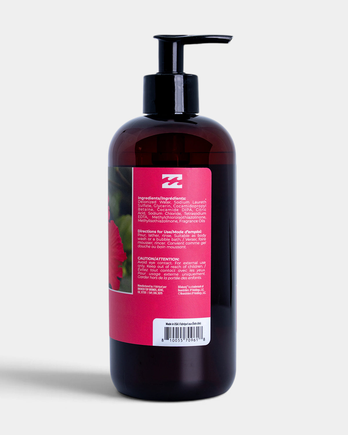 A dark amber plastic pump bottle with a black dispenser, showing the back label with text and a pink brand logo, on a light gray background.